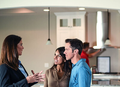 An agent talking with home buyers with a HomeTeam home inspector in the background